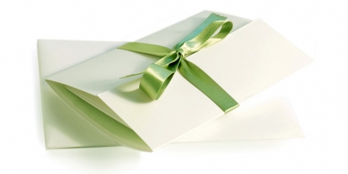 a simple and elegant wedding invitation tied with a green silk ribbon